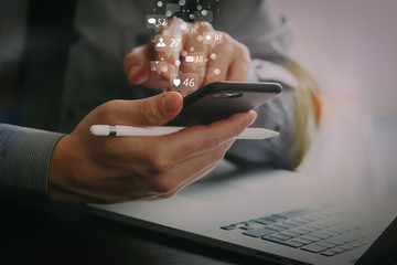close up of businessman working with mobile phone and stylus pen and laptop computer on wooden desk...