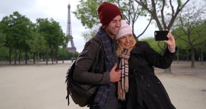 Loving young couple take a selfie near the Eiffel Tower, Portrait of smiling male and female tourists taking a picture in Paris, 4k