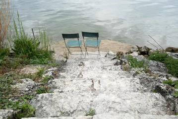 Zelfklevend Fotobehang two empty chairs on the lake shore at the bottom of old rocky stairs with a great view behind © makasana photo