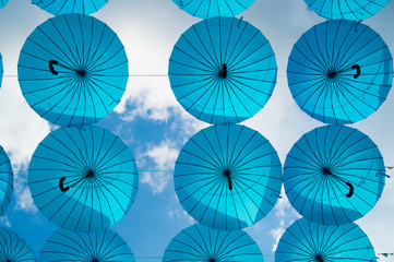 Blue umbrellas float in sky on sunny day. Umbrella sky project installation. Holiday and festival celebration. Shade and protection. Outdoor art design and decor