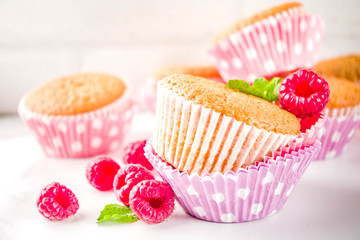 Sweet summer dessert, homemade baked muffin with raspberry jam, served with tea, fresh raspberries and mint. On a white marble table, copy space