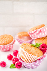 Sweet summer dessert, homemade baked muffin with raspberry jam, served with tea, fresh raspberries and mint. On a white marble table, copy space