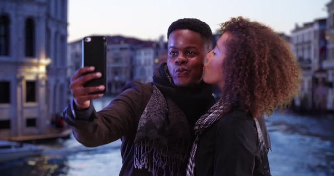 Attractive tourist couple take selfie by Grand Canal at night, Millennial black male and female pose for a fun picture in Venice at night, 4k