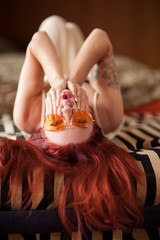 pretty young woman with red hair and sunglasses lies relaxed and laughing on the couch, emotion...