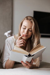 Curious young woman reading blank cover open book