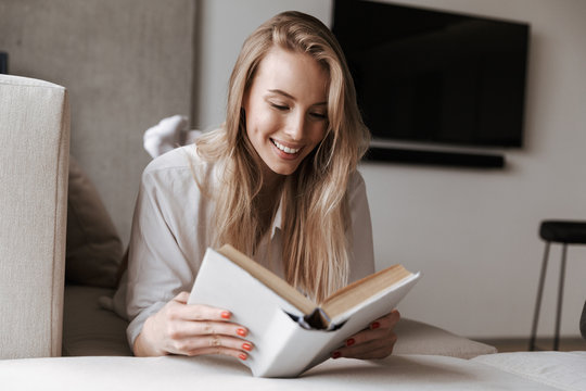 Smiling young woman reading blank cover open book