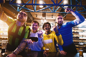 Fototapeta na wymiar Cheerful soccer fans are passionately cheering for their teams victory in a pub.