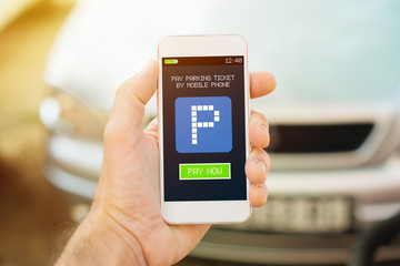 Man using smartphone app to pay car parking ticket