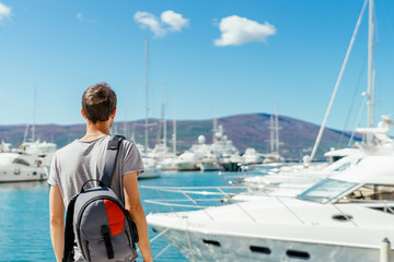 Young tourist looking at beautiful marina with luxurious yachts