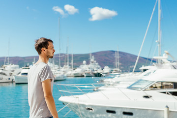 Young man looking at beautiful marina with luxurious yachts