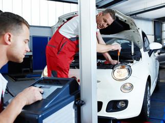 Car mechanic testing light of car in garage