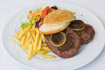 Burger with chips on white plate on white background