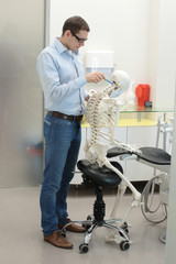 dentist as a patientexpert analysing  human skeleton model as a dentist  in sitting,leaning position at work - occupational disease concept