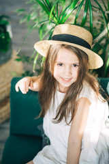 Smiling preschooler girl in a straw boater hat looking at the camera. Summer vacation concept. Vertical orientation