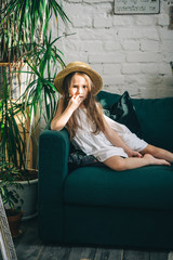 Cute little girl is lying on the green sofa\couch indoor plants around. Summer vacation begins. Vertical orientation