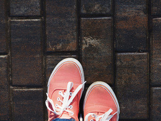 a pair of pink sneakers on the wet asphalt