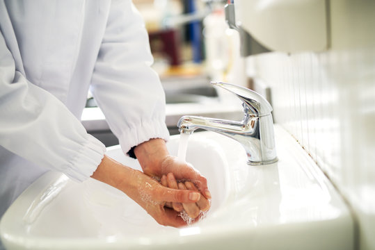 Female hands are being washed clean in a bathroom sink.