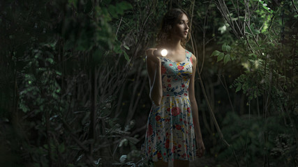 Girl with a lantern at night in a dark forest