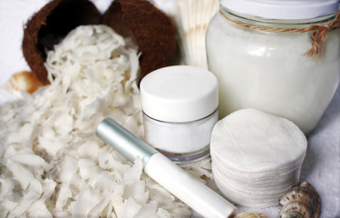 Fototapeta na wymiar Sliced coconut pulp as an ingredient for coconut oil. A concept for facial and body care at home or procedures in the beauty spa. Cosmetic jars without logo: mocap, copy space.