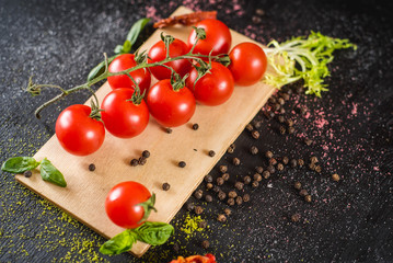 Fresh cherry tomatoes and spices on black background. Top view. Copy space