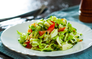 fresh vegetables salad with cabbage, tomato and cucumber in plate on table