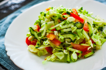 fresh vegetables salad with cabbage, tomato and cucumber in plate on table