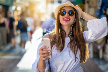Junge, fröhliche, attraktive Frau in der Stadt beim Shoppen mit Telefon in der Hand
