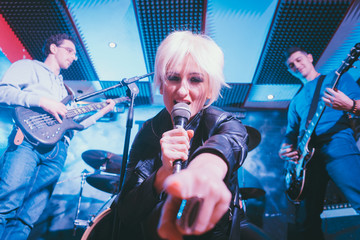 Band during gig making rock music on stage together 