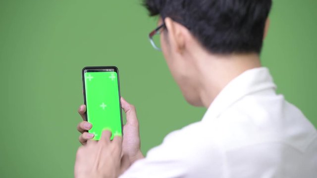 Young Asian businessman using phone while showing copy space