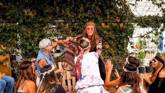 party style sun flowers ’60 years like hippy people. young beautiful women in friendship having fun all together in a natural outdoor location. slow motion movie with more than 10 friends