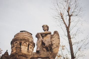 Gloomy monuments of the cemetery on sunny autumn aftetnoon. Abandone lonely statue of a stone angel