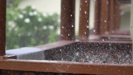 CLOSE UP, DOF: Monsoon rain washes the brown metal railing on balcony of a lovely vacation house with a beautiful view of the exotic backyard. Tropical rain soaks the white towel left out to dry. - Powered by Adobe