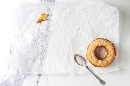 Last Homemade Puff Pastry Deep Fried Donut Or Cronut With Sugar On Crumpled Paper Over White Marble Texture Background. Flat Lay, Space.