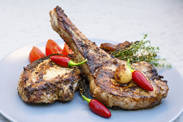 Рork steaks on a plate with chili, tomatoes