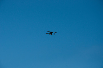 Black quadrupter with propellers flies in the sky and photographs landscapes