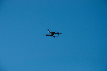 Black quadrupter with propellers flies in the sky and photographs landscapes