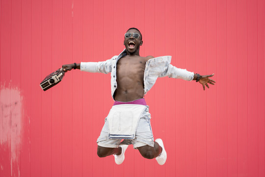 Young man holding a radio while jumping