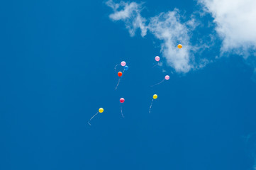 Many balloons flying into the sky. Multicolored balloons in the sky with clouds