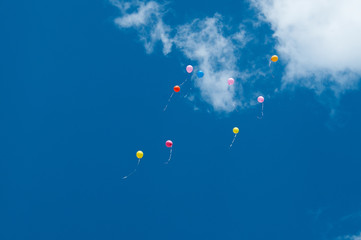 Many balloons flying into the sky. Multicolored balloons in the sky with clouds