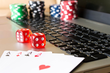 Dice, poker chips and playing cards on laptop. The concept of online games