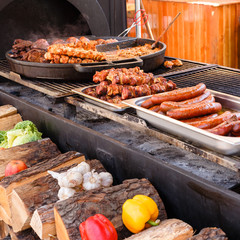Delicious fresh fried meat and sausages on a pans in a street cafe.