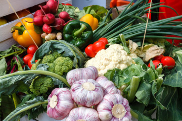 Fresh vegetables - garlic, cauliflower, greenery, onion on a picnic table on a summer day.