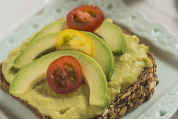 Green Avocado Spread and Organic Slices with Fresh Cherry Tomato as Vegan Breakfast Concept