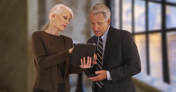 Male and female office workers using digital tablet, Portrait of two senior executives using technology inside the office, 4k