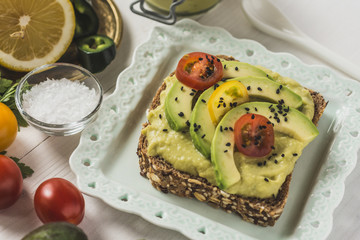 Green Avocado Spread and Organic Slices with Fresh Cherry Tomato as Vegan Breakfast Concept