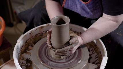 Close up shot of a hands of a female pottery crafting new vase in the workshop.