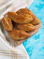 Delicious pies on the blue table. Small pies with cabbage. Homemade cake.