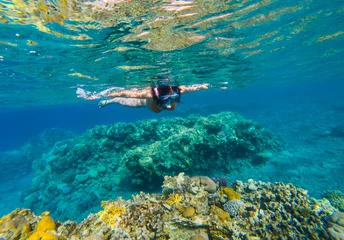 Rolgordijnen Vrouw snorkelt boven koraalrif © salajean