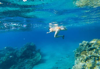 Poster Woman snorkeling above coral reef © salajean
