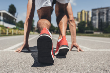 back view of male sprinter in starting position on running track